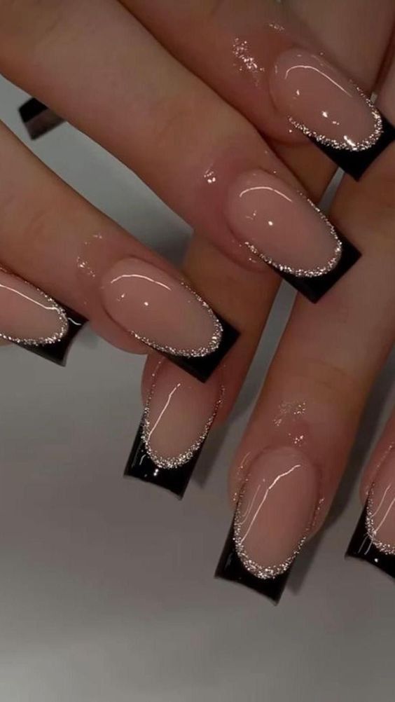 Long square-shaped nails with a glossy nude base and sleek black French tips, highlighted by a shimmering silver glitter outline along the smile line of each nail.