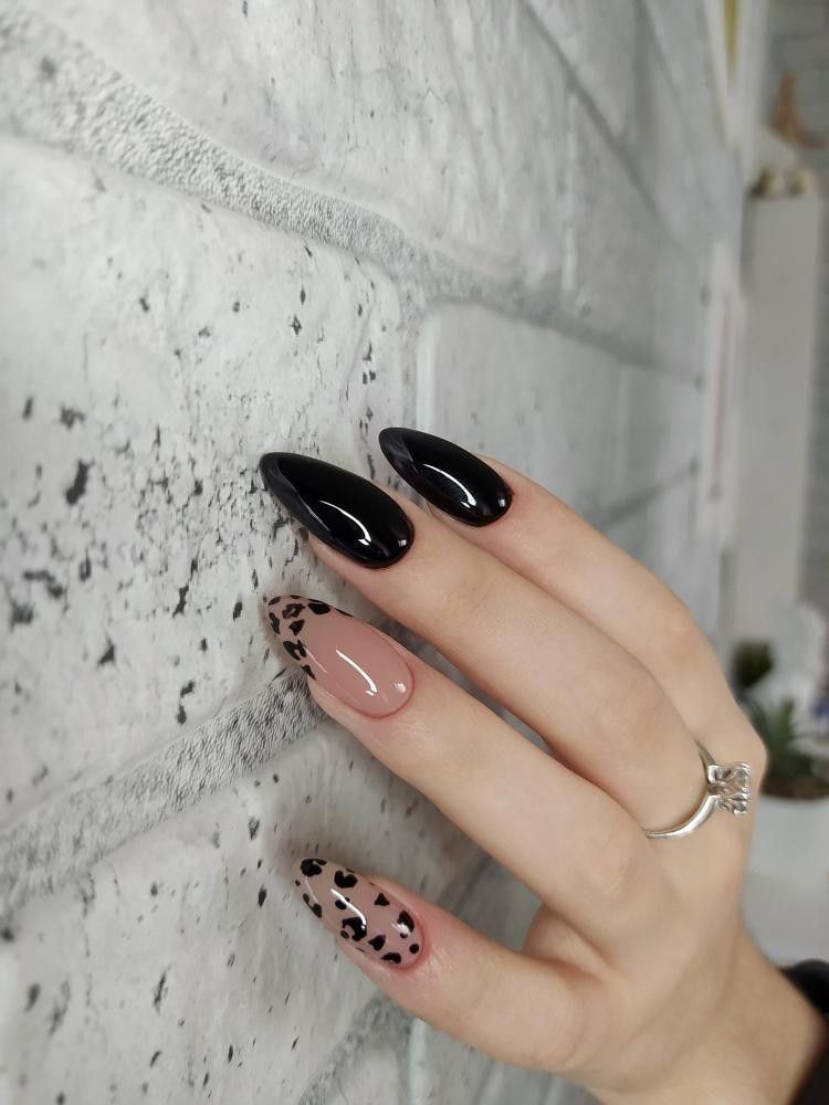 High-gloss black almond-shaped nails paired with nude-pink accent nails featuring black leopard print, with one accent nail fully covered and the other styled as a French tip.