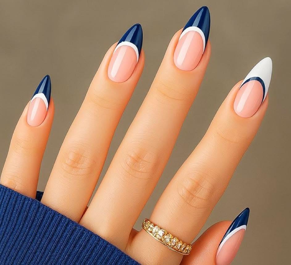 Almond-shaped manicured nails with a glossy natural pink base, featuring dark navy blue French tips lined with a thin white border, and one accent nail with a white tip lined in navy blue.