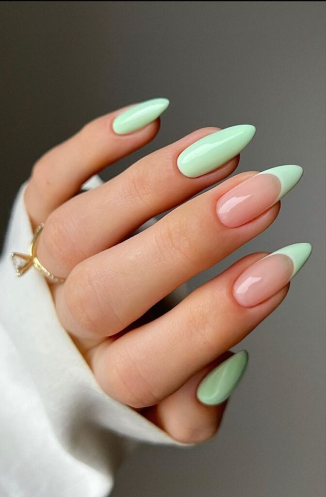 Medium-to-long almond-shaped nails featuring a high-gloss finish with a mix of solid pastel sage green polish on the thumb, index, and pinky fingers, and a sheer natural pink base with matching sage green French tips on the middle and ring fingers.