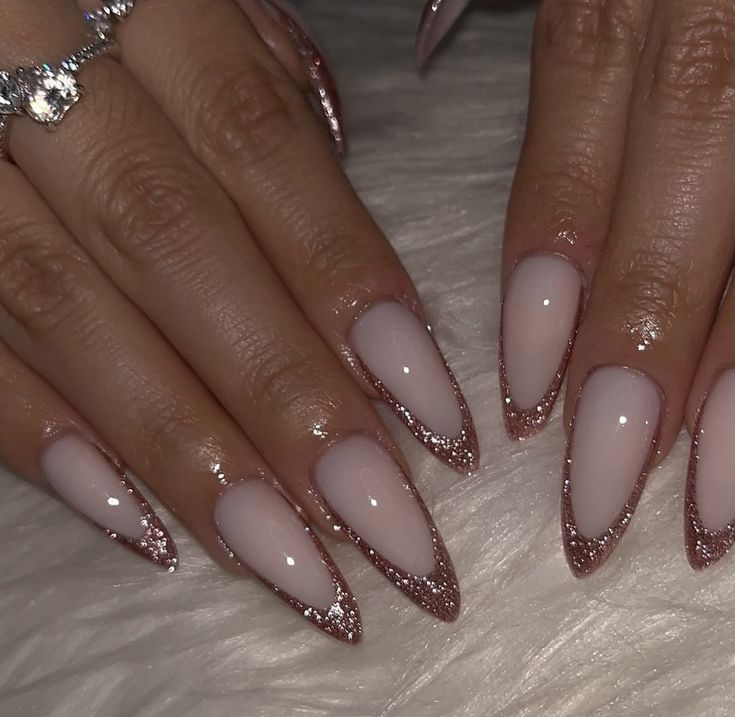 Long almond-shaped nails featuring a high-gloss, milky pink base coat and elegant, deeply curved French tips painted with reflective rose gold glitter.