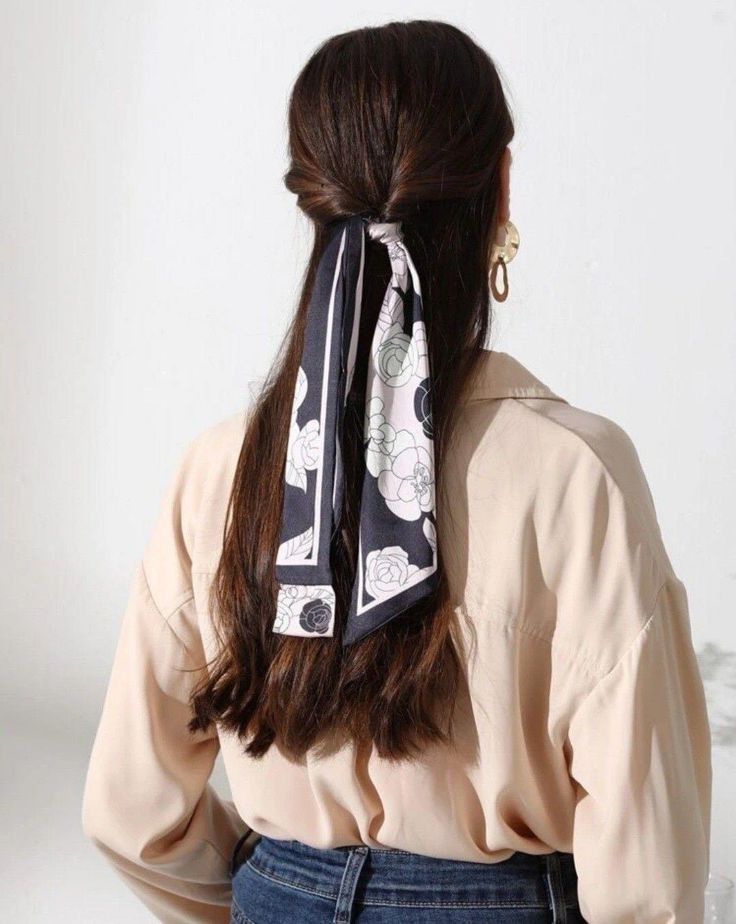 Back view of a woman showing how to style a bandana or scarf. A black and white floral skinny scarf is tied around a simple half-up twisted hairstyle.