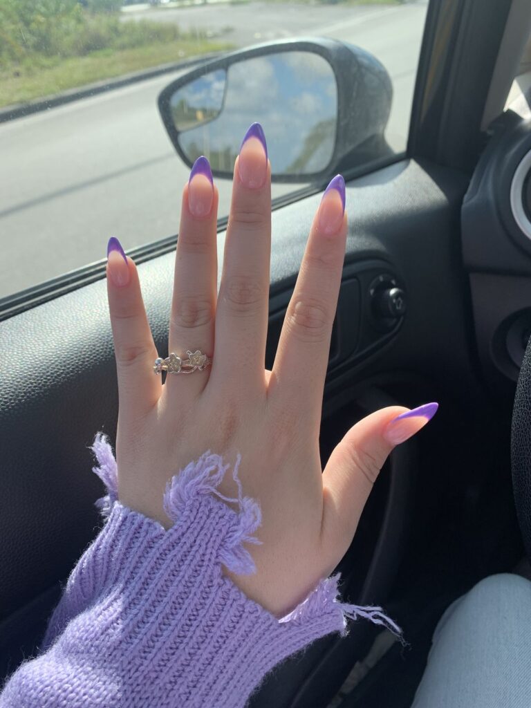 Long almond-shaped nails with a glossy natural pink base coat, featuring clean and vibrant lavender purple French tips on every finger.