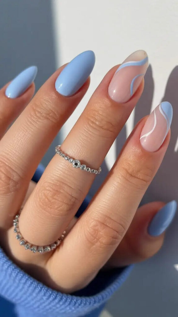 Elegant blue swirl nail design on almond-shaped nails with an ocean-inspired look.