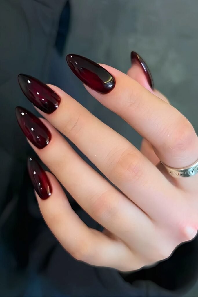 Glossy burgundy cat eye nails with a magnetic shimmer on elegant almond-shaped nails.