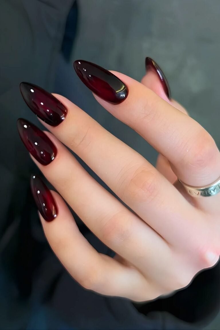 Long almond-shaped velvet acrylic nails featuring a deep, moody dark wine burgundy shade with a glowing magnetic cat eye nail designs effect.