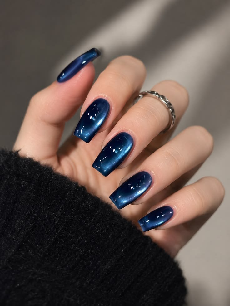 Navy blue cat eye nails with a glossy magnetic shimmer on square-shaped nails.