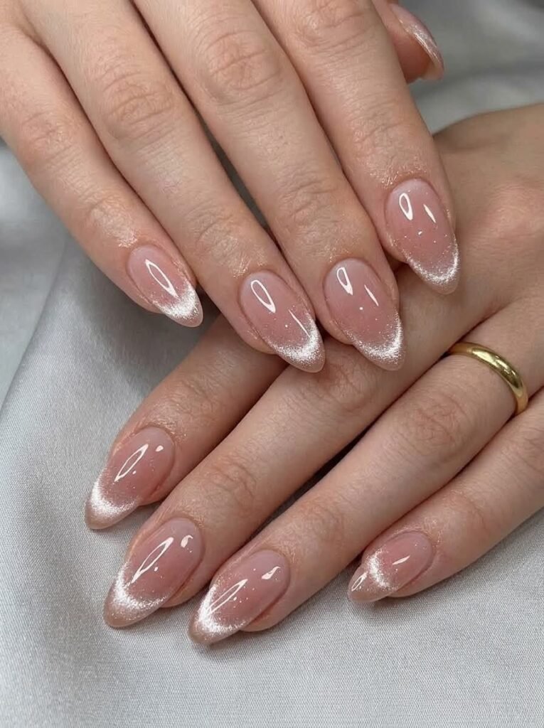 Elegant almond-shaped nails featuring a natural sheer pink base and radiant silver magnetic French tips creating classic cat eye nail designs.