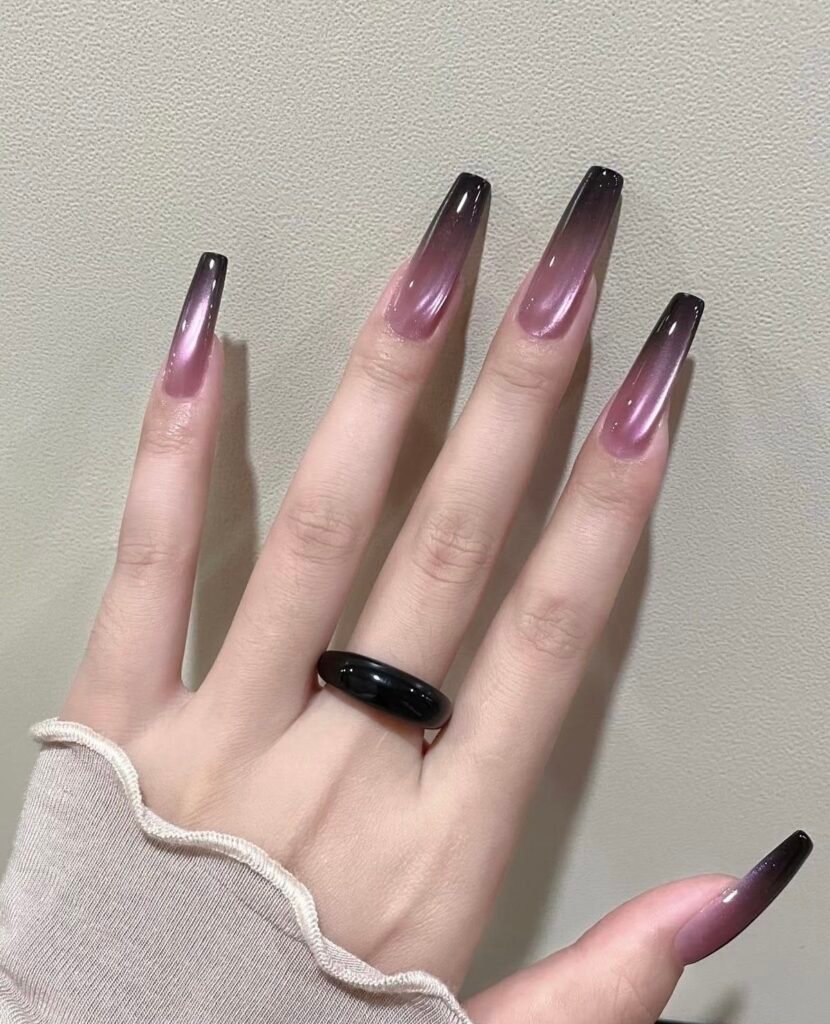Long coffin-shaped nails with a dusty rose jelly base, black ombre tips, and a bright silver-pink magnetic streak creating dramatic cat eye nail designs.