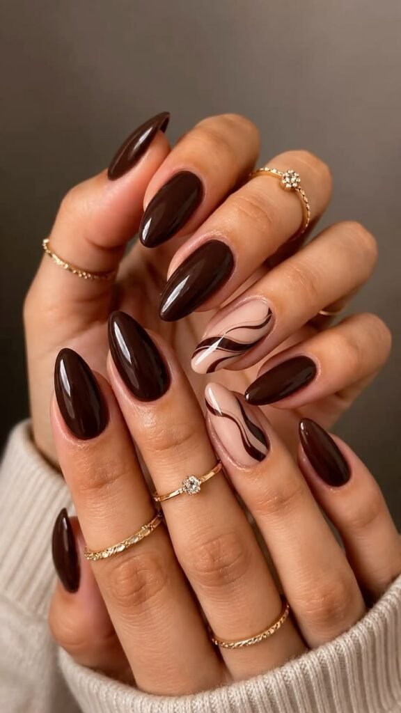 Espresso brown fall nails with cream accent nails featuring dark brown abstract swirls, glossy almond-shaped manicure, and cozy autumn nail art design.