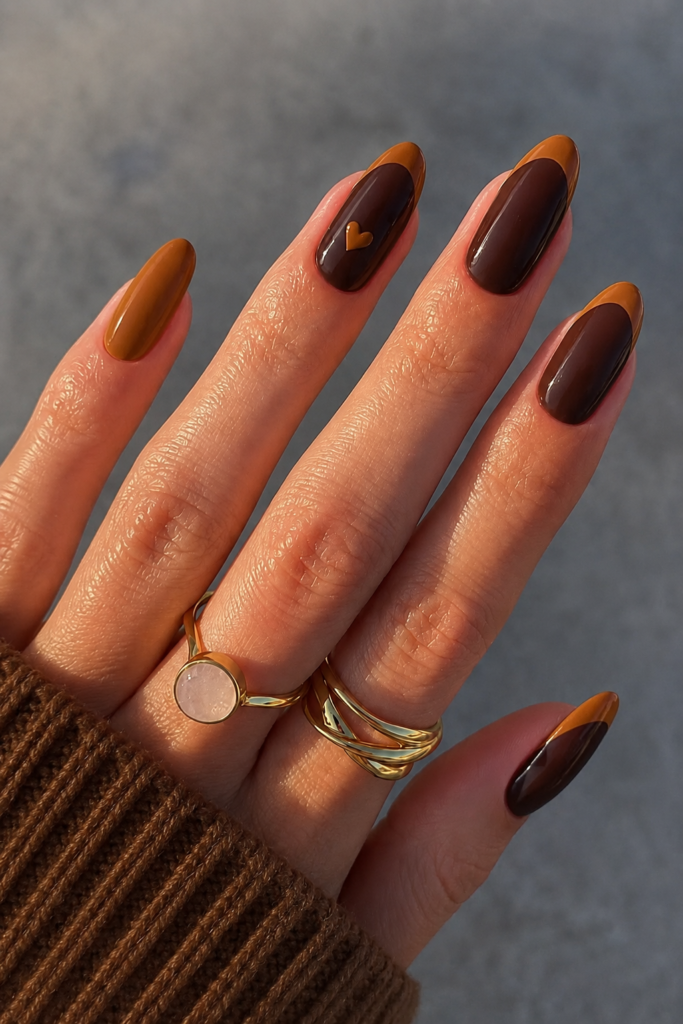 Chocolate brown and caramel color block almond nails with a tiny heart accent, creating elegant fall nail ideas for autumn.