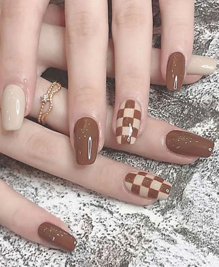 Glossy mocha brown and cream square nails featuring a trendy checkerboard accent design, creating a chic and playful fall manicure.
