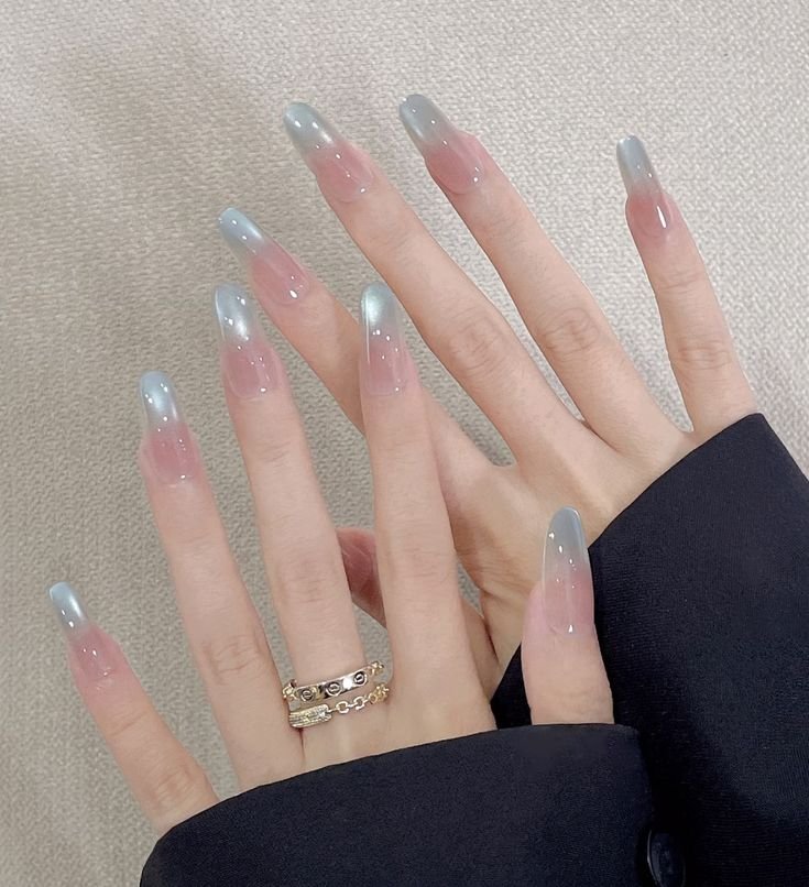 Long, square-oval jelly nails featuring a sheer pink blush base and luminous icy-blue magnetic French ombre cat eye nail designs on the tips.