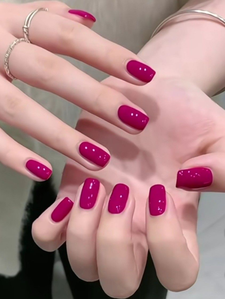 Rich magenta berry nails, glossy short squoval manicure, and vibrant solid berry pink-purple minimalist nail design with silver jewelry.