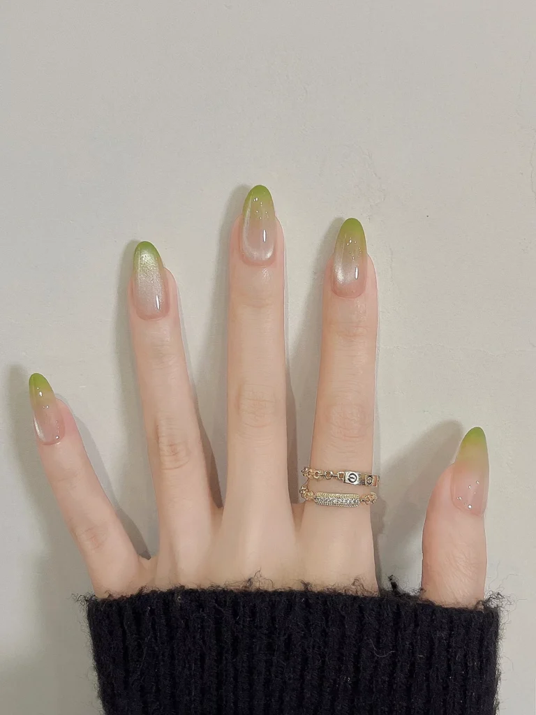 Long oval-shaped nails with a sheer nude jelly base, vibrantly blended matcha green ombre tips, and a central glowing silver magnetic cat eye nail designs effect.