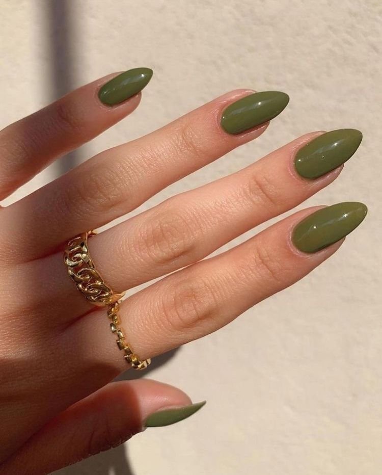 Glossy olive green almond-shaped nails with a minimalist solid color manicure and gold rings.