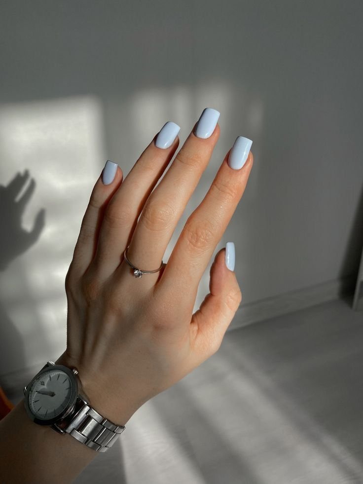 Glossy baby blue square-shaped nails with a minimalist solid color manicure and silver jewelry.