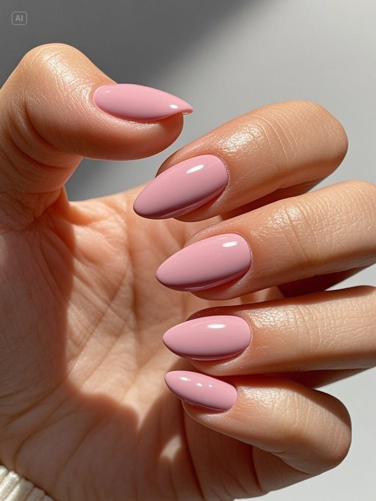 Glossy soft blush pink almond-shaped nails with a minimalist solid color manicure.