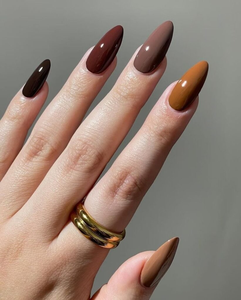Glossy almond nails featuring chocolate brown, caramel, taupe, and mocha color block designs, creating elegant earth-tone fall nail ideas for autumn.