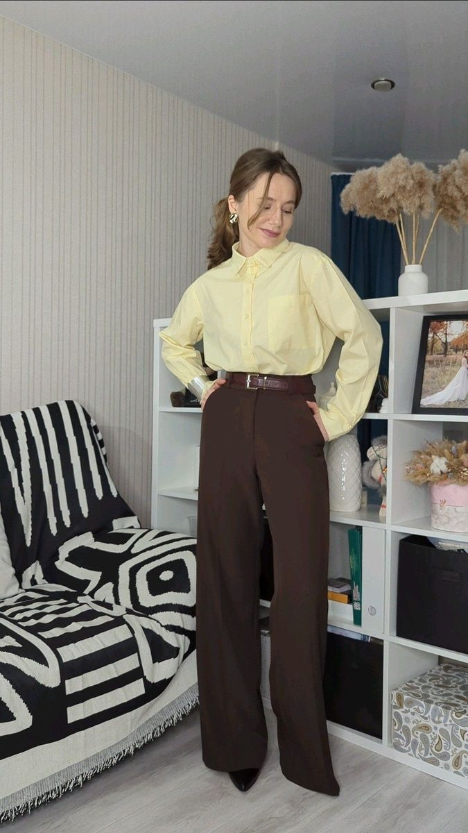 Woman wearing a pale yellow button-down shirt with brown wide-leg pants, a brown belt, and pointed-toe heels.