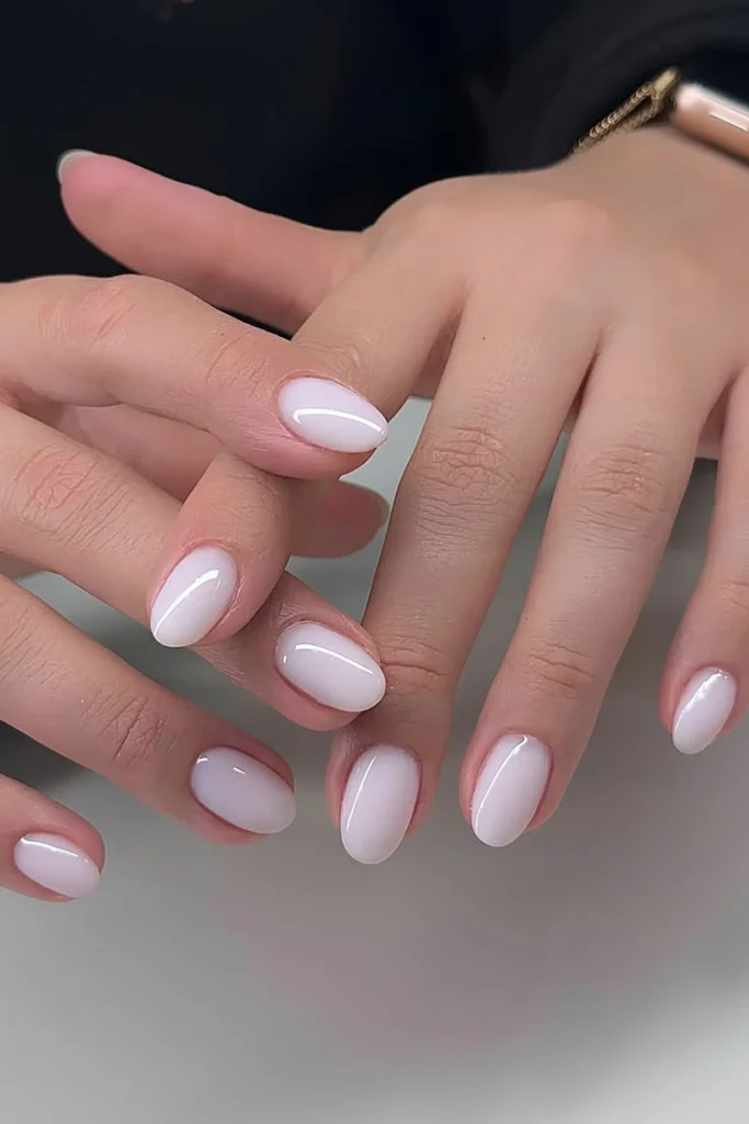 Milky white manicure on short round nails with a soft semi sheer creamy white polish.