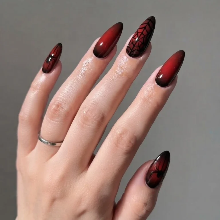 A close-up beauty shot of luxurious nail designs featuring almond-shaped red and black ombre nails with intricate spider web and spider art.