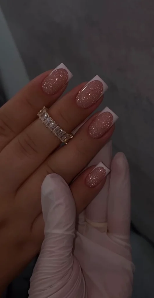 A close-up view of a sophisticated square-shaped French manicure featuring a sparkling nude base, crisp white tips, and a glossy diamond-like finish perfect for a chic luxury nail look.
